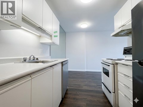A kitchen with white cabinets and a black fridge.