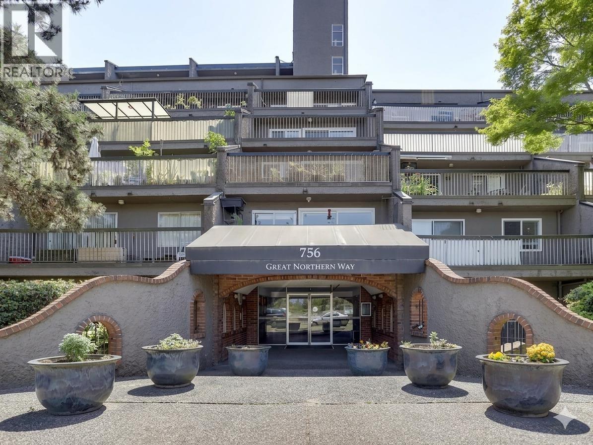 The entrance to a building with the sign "Great Northern Way" is surrounded by large planters.