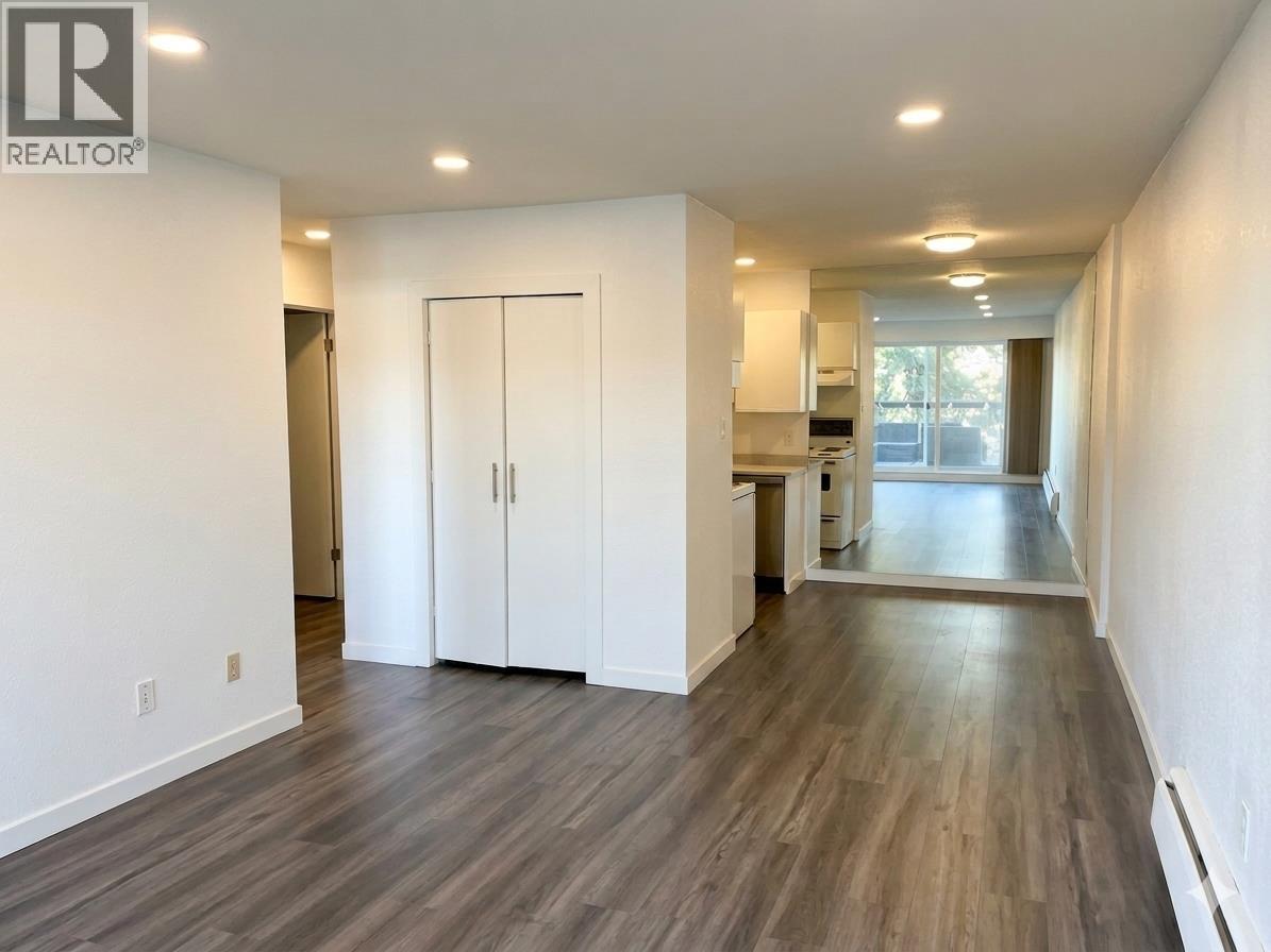 A spacious room with wood flooring and white walls.