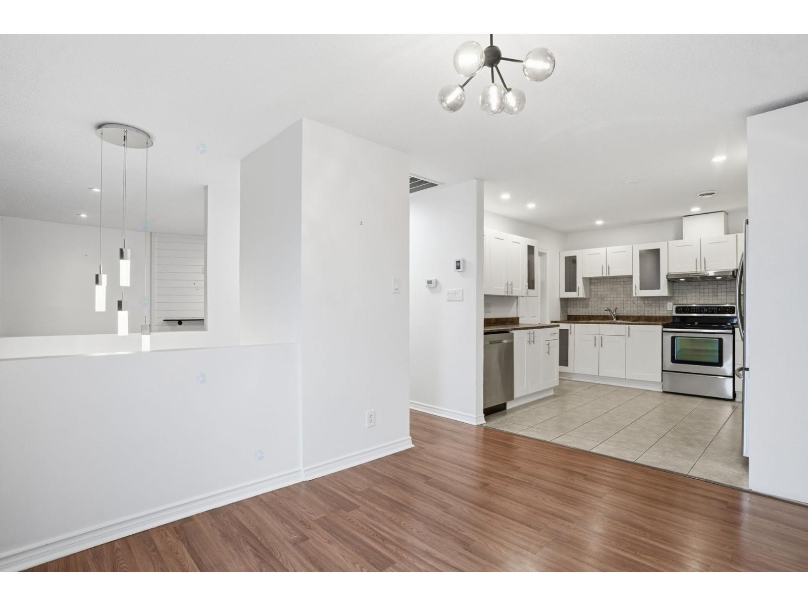A kitchen with white cabinets and a wooden floor.