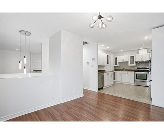 A kitchen with white cabinets and a wooden floor.