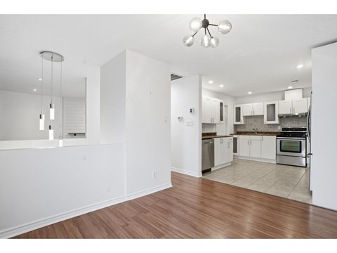 A kitchen with white cabinets and a wooden floor.
