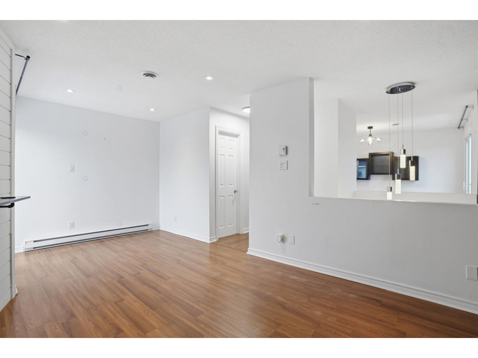 A spacious room with wooden floors and white walls.