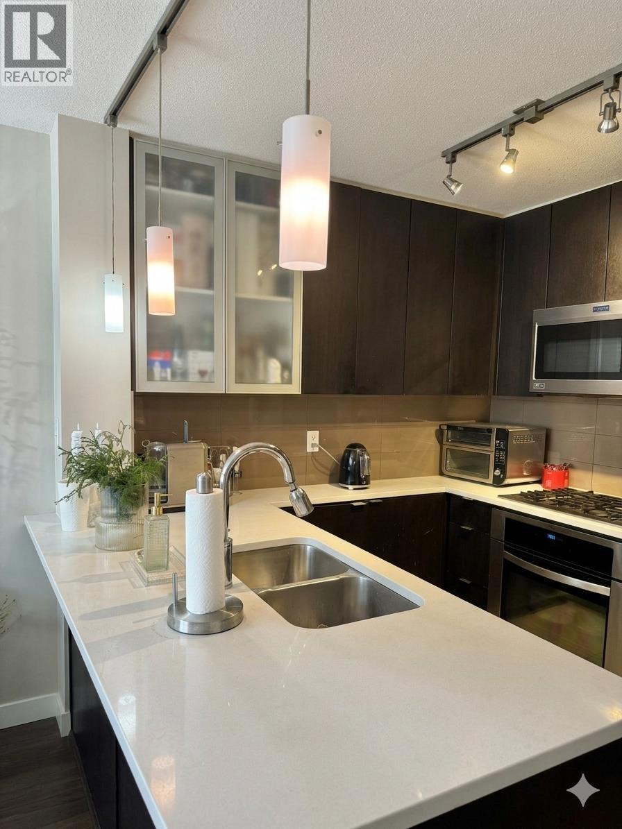 A modern kitchen with a white countertop and stainless steel appliances.