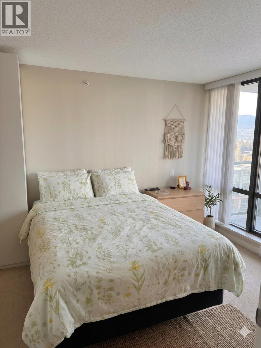 A bed with a white floral comforter and pillows in a bedroom.
