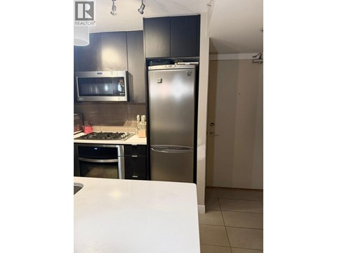 A kitchen with a stainless steel refrigerator and a white counter.