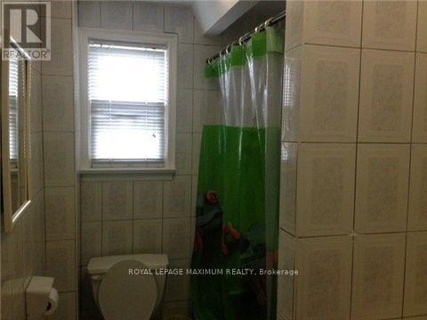 A bathroom with a toilet, a window, and a shower curtain.
