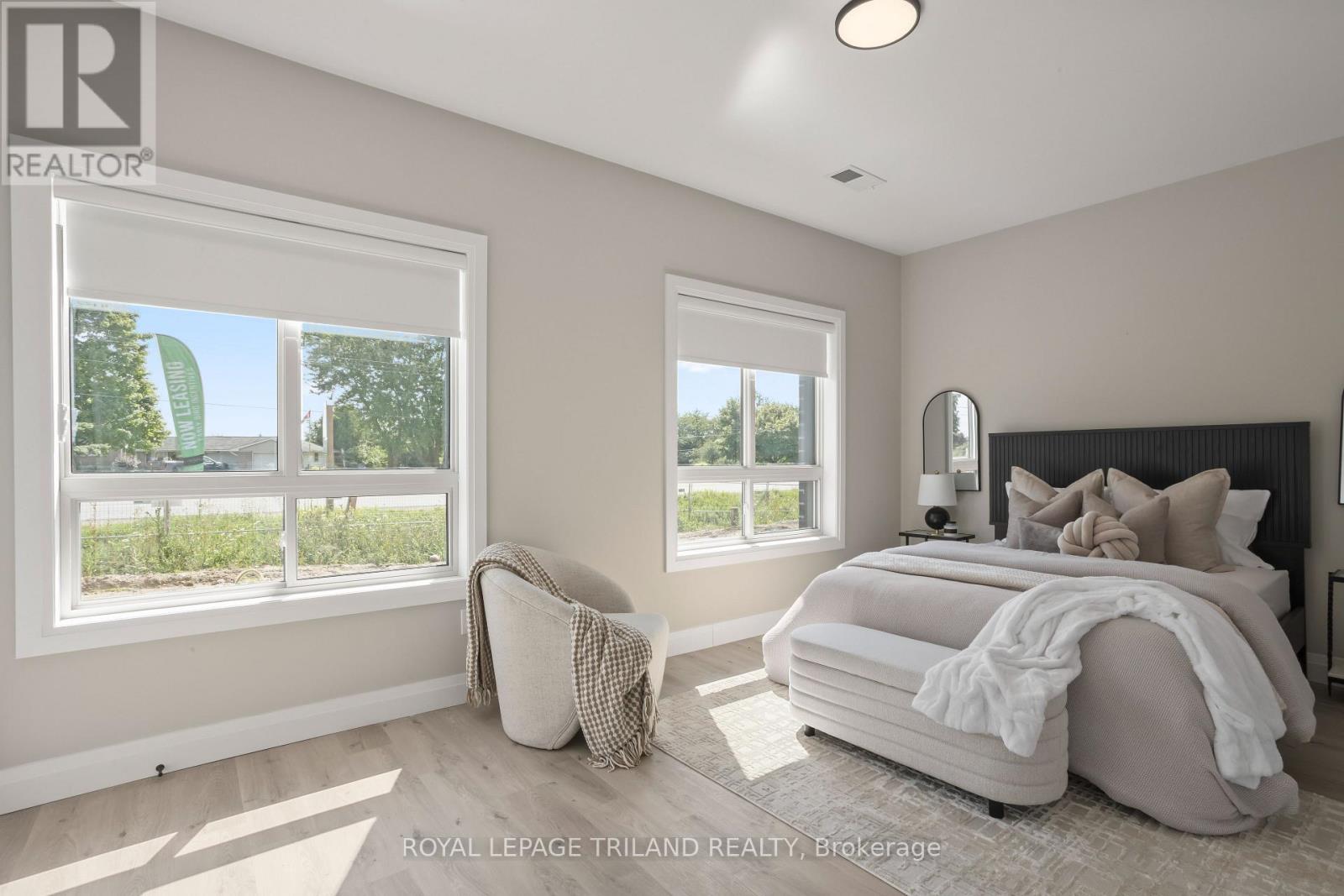A bedroom with a large bed and a window overlooking a green area.