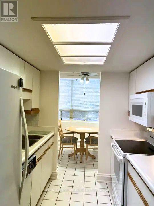A kitchen with white appliances and a table with chairs.