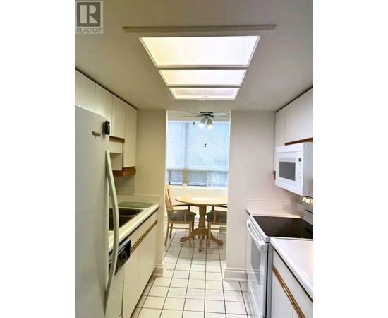 A kitchen with white appliances and a table with chairs.