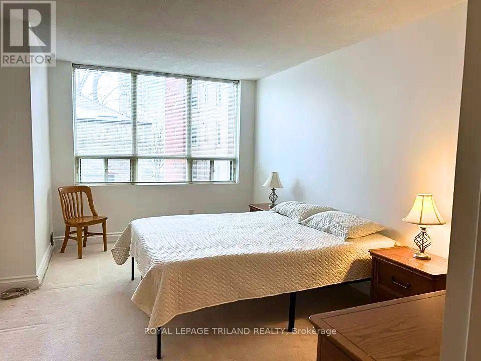 A bedroom with a bed, chair, and lamp.