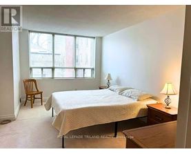 A bedroom with a bed, chair, and lamp.