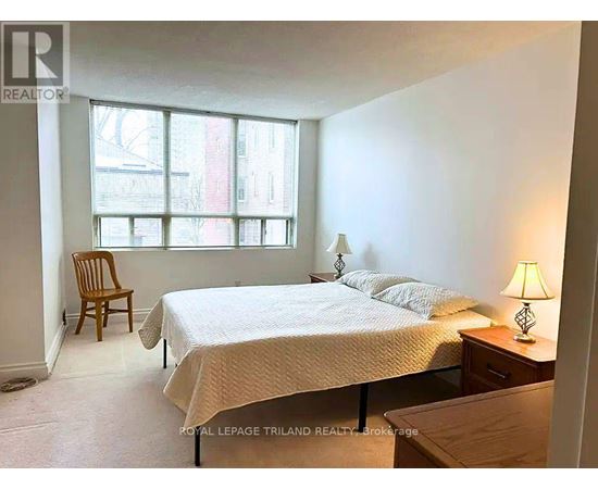 A bedroom with a bed, chair, and lamp.