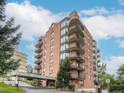 A multi-story residential building with balconies and a Centino sign on the ground.