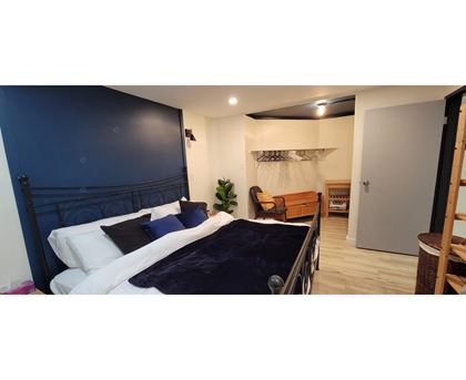 A bedroom with a dark blue headboard and white bedding.