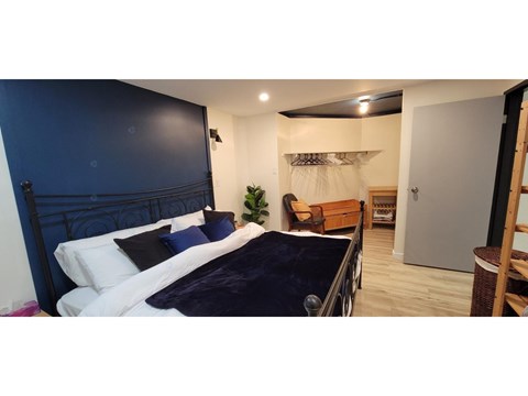 A bedroom with a dark blue headboard and white bedding.