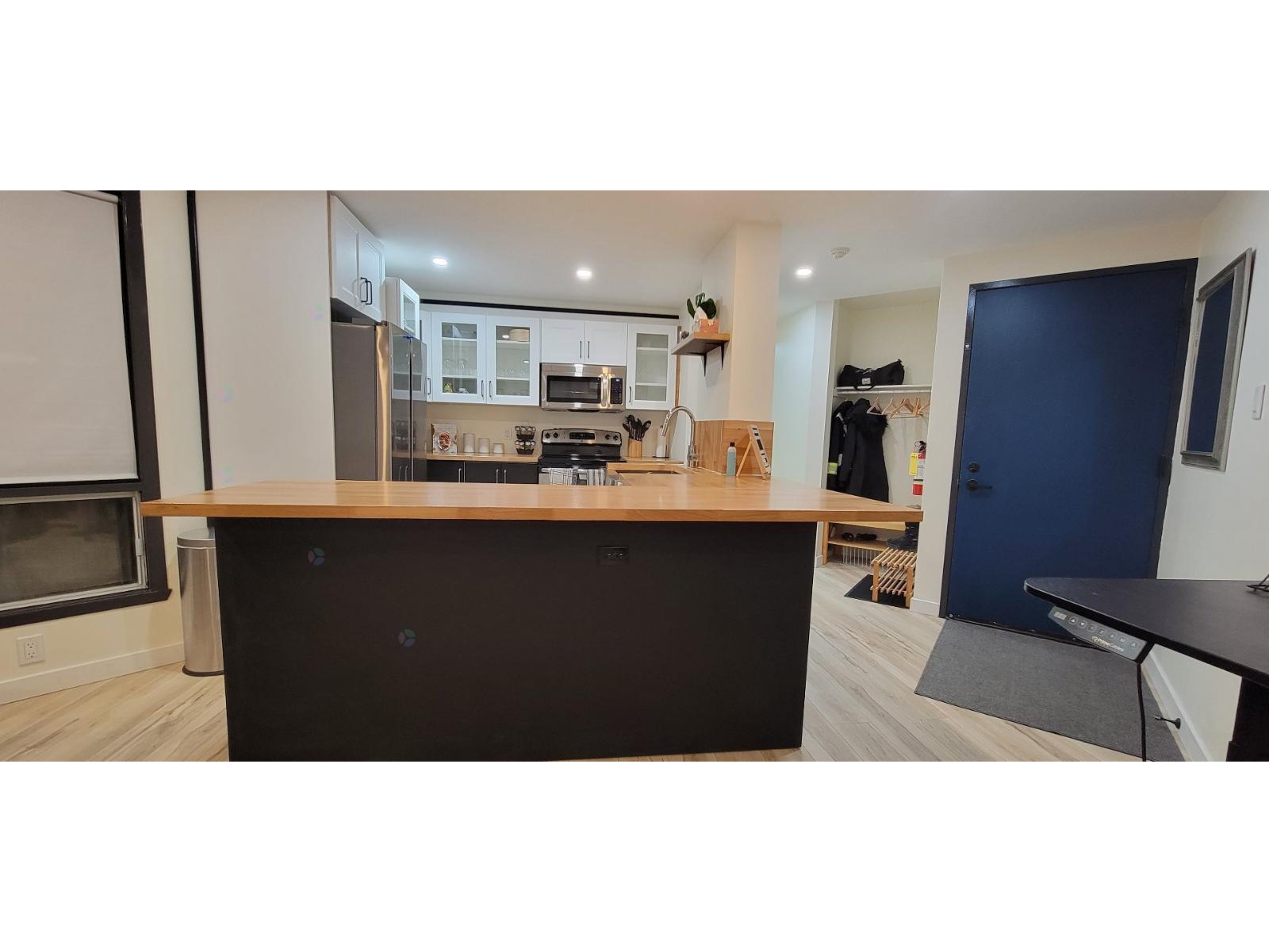 A kitchen with a black countertop and a blue door.
