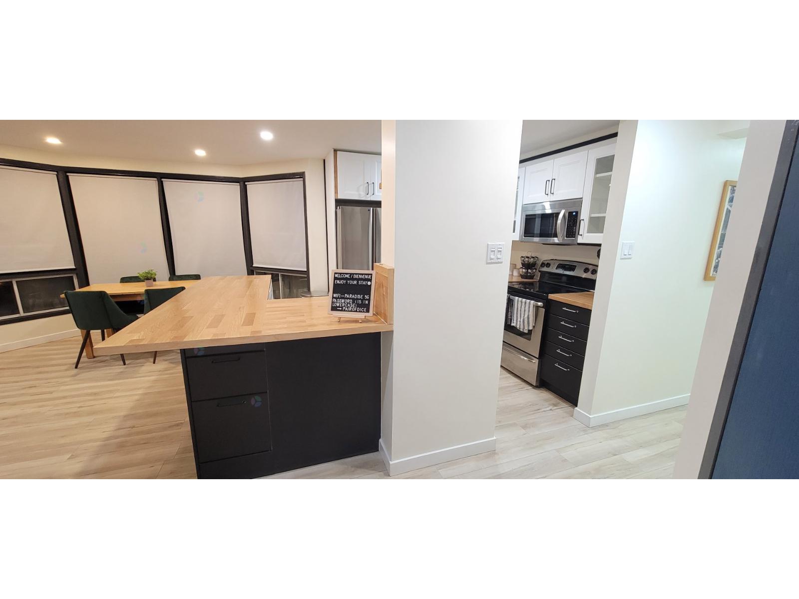 A modern kitchen with a wooden counter and black drawers.