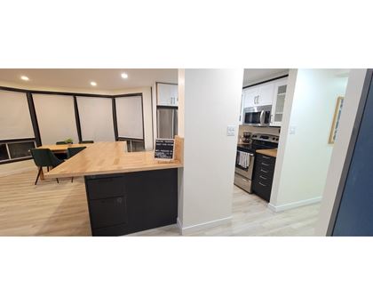 A modern kitchen with a wooden counter and black drawers.