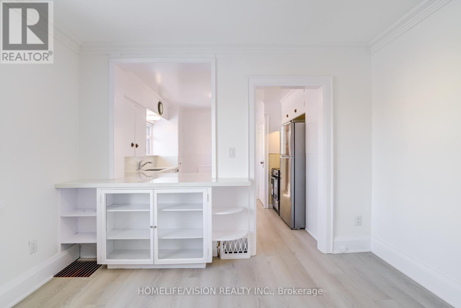 A white kitchen with a refrigerator and cabinets.