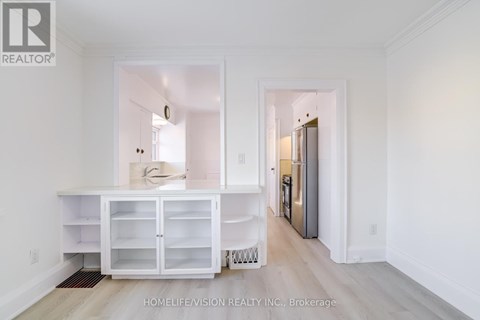 A white kitchen with a refrigerator and cabinets.