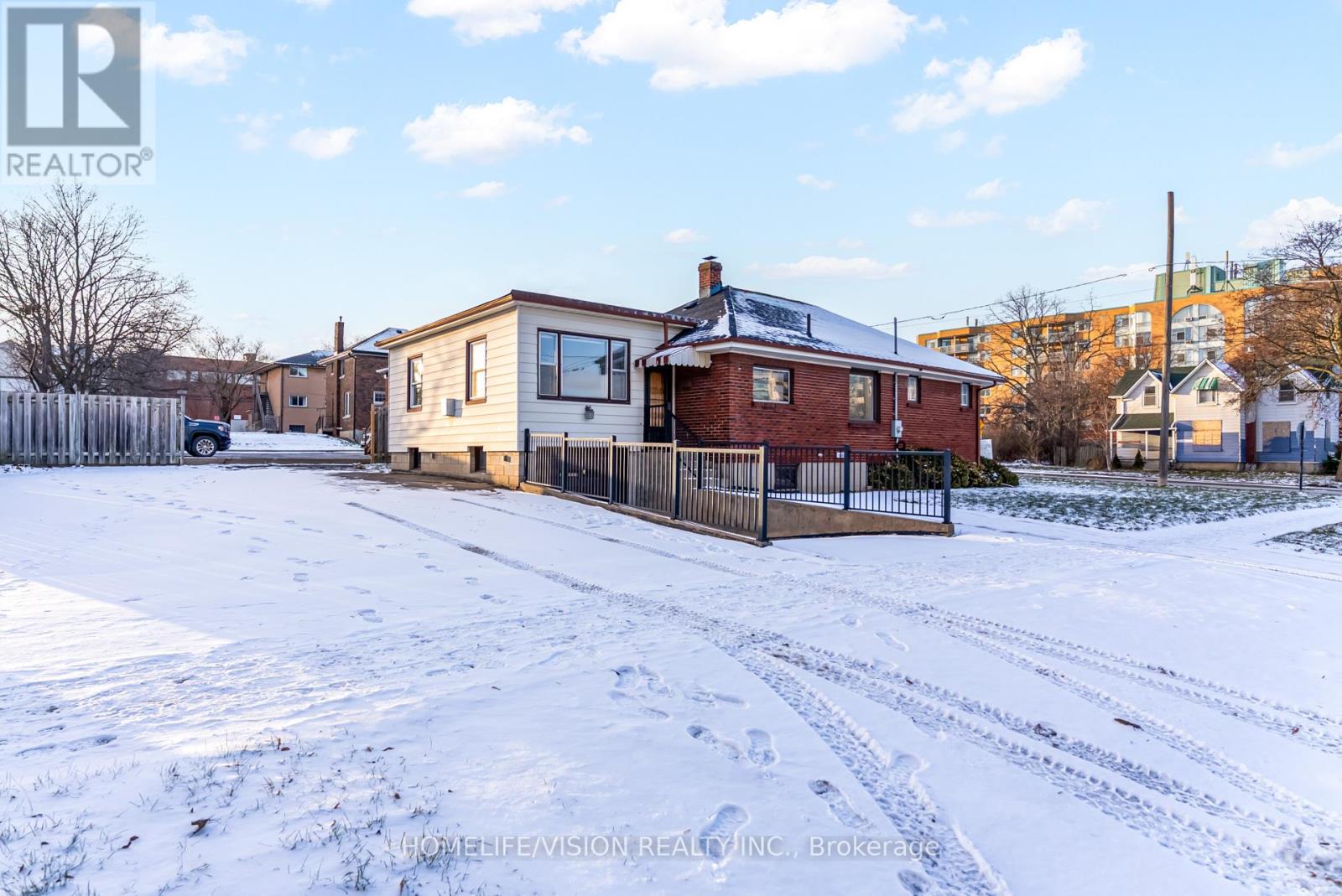 A snow-covered ground with a house and a fence in front.