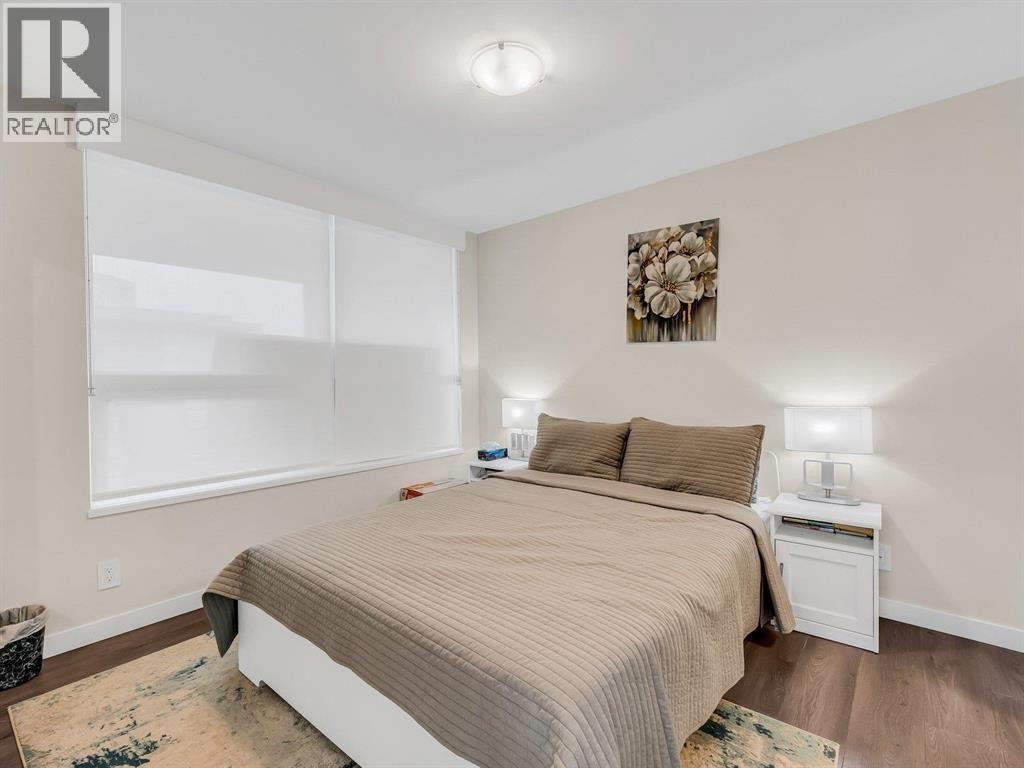 A bedroom with a large bed and a nightstand with a lamp.