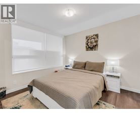 A bedroom with a large bed and a nightstand with a lamp.