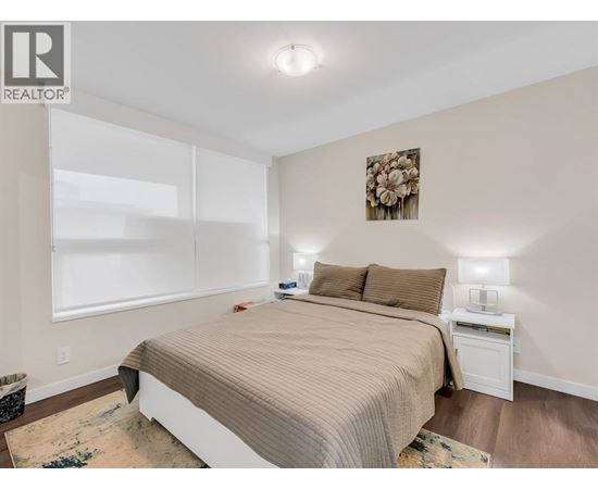 A bedroom with a large bed and a nightstand with a lamp.
