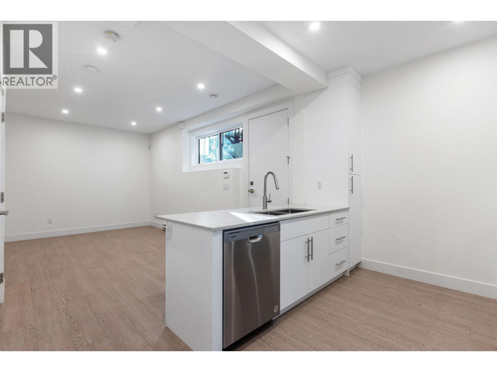 A white kitchen with a dishwasher and a window.