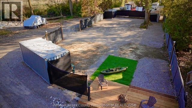 A backyard with a kayak on a green mat and a wooden deck.