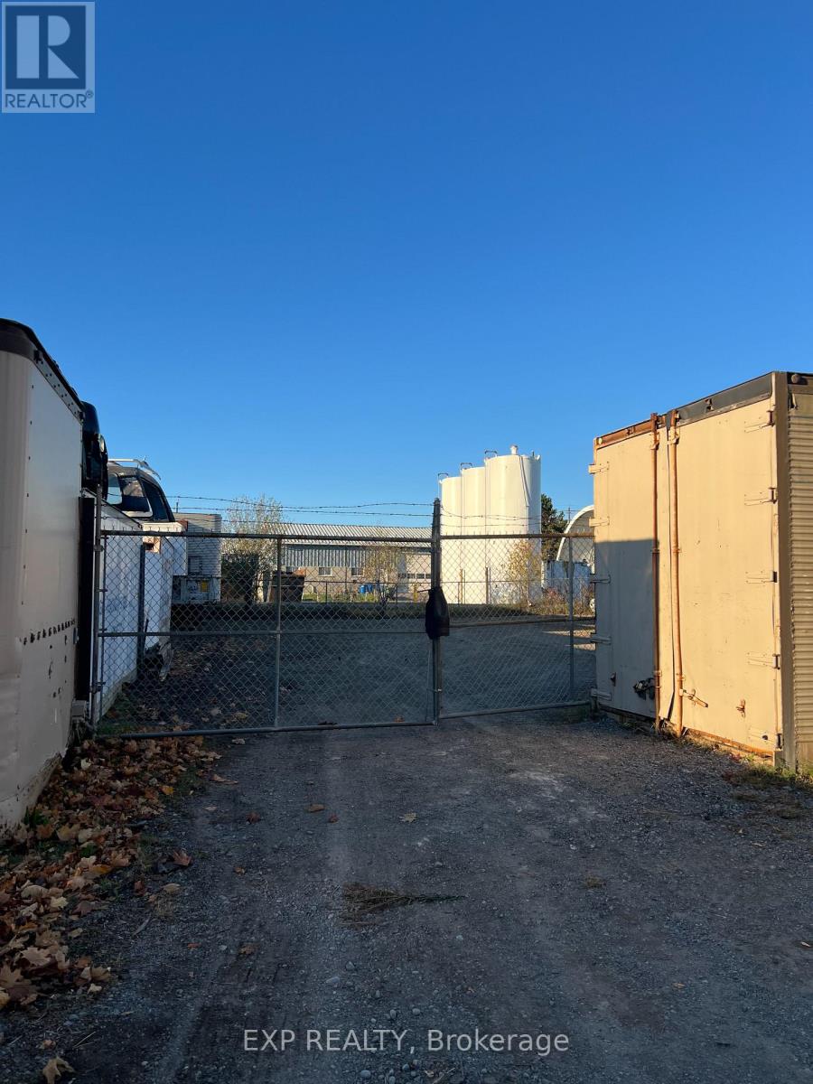 A large white tank is behind a chain link fence in a lot.
