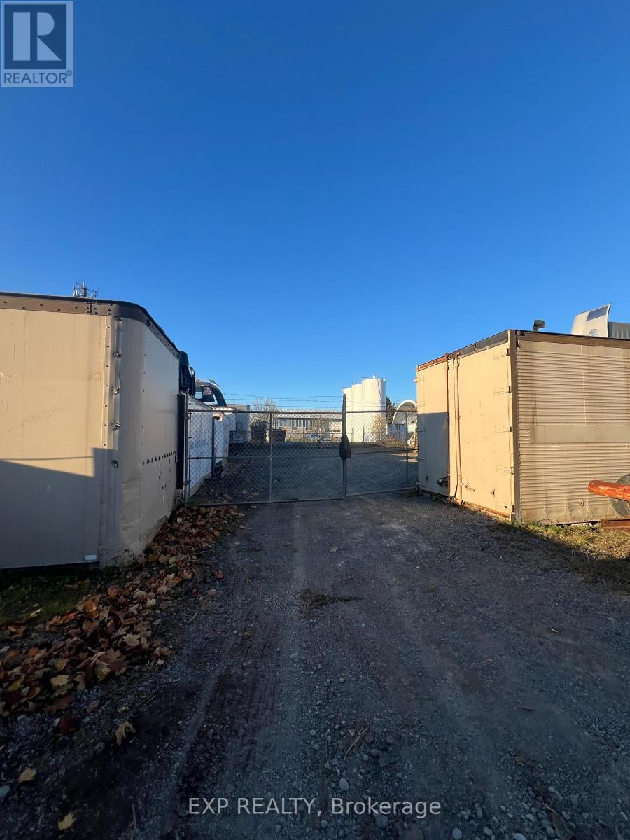 A dirt road leads between two buildings with a sign that says EXP REALTY Brokerage.