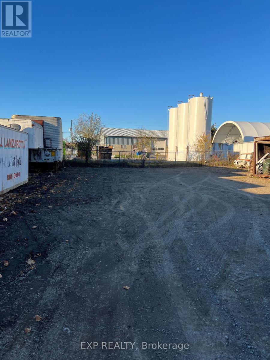 An exp realty brokerage sign is on a dirt lot.