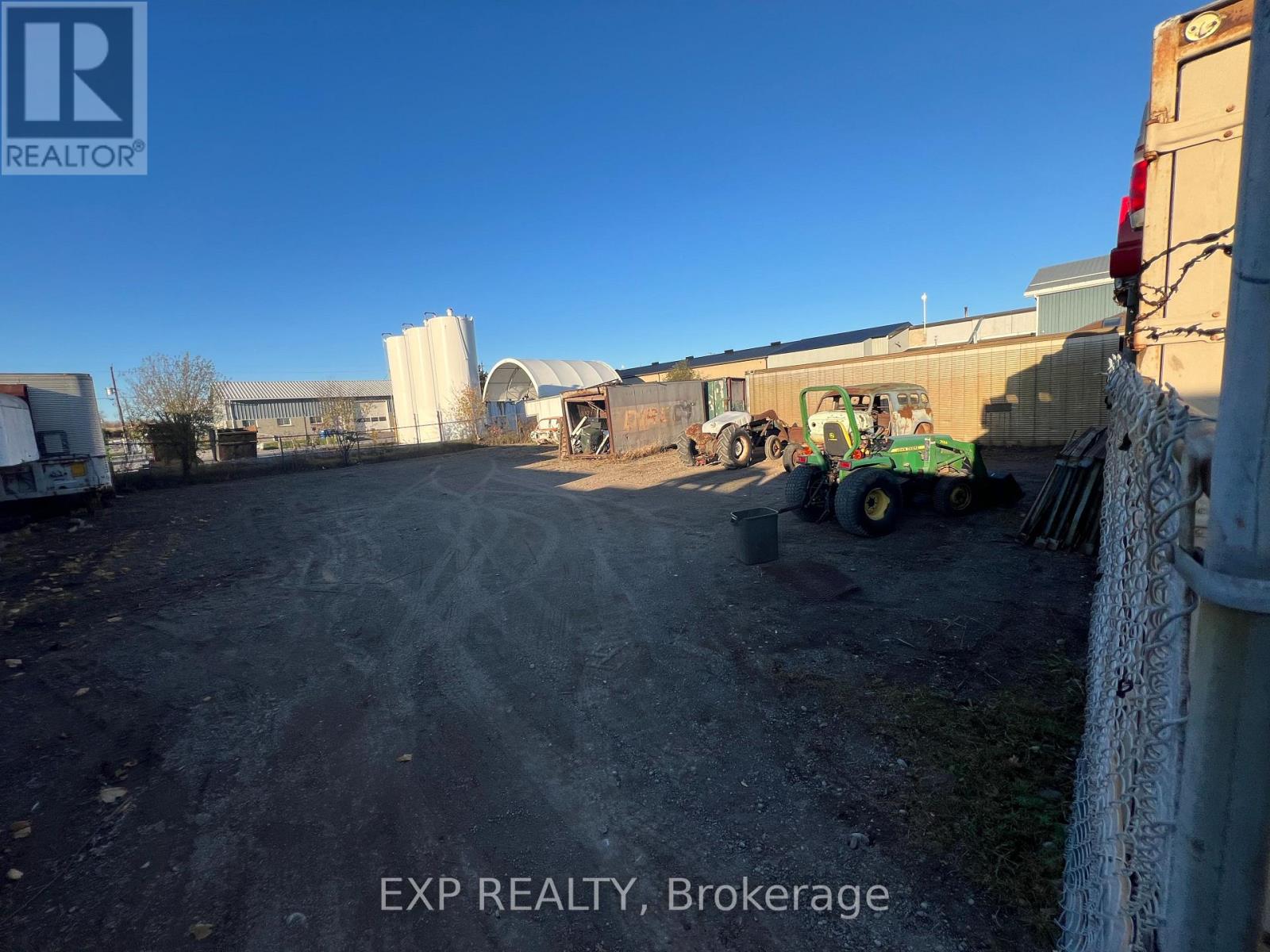 A dirt field with a tractor and a building in the background.