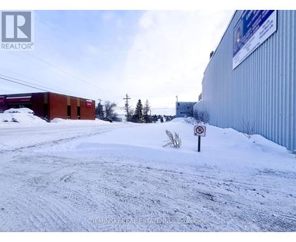 A snow-covered ground with a no parking sign in the foreground.