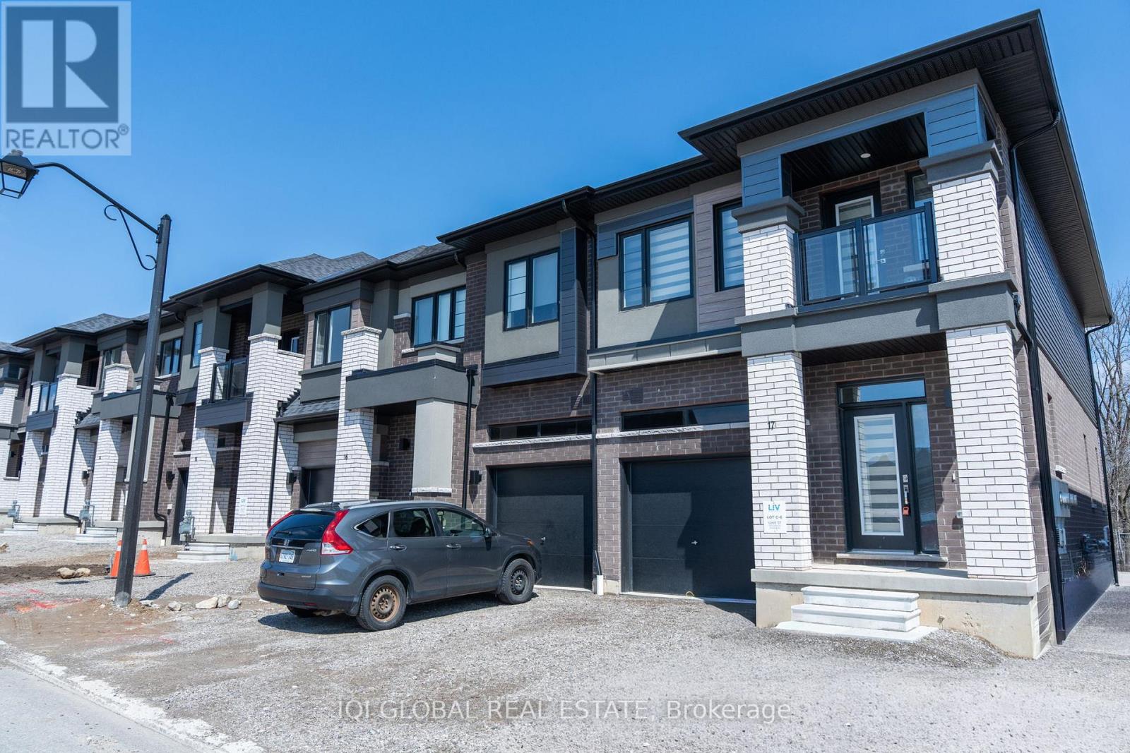 A grey car is parked in front of a building with a sign that says REALTOR.