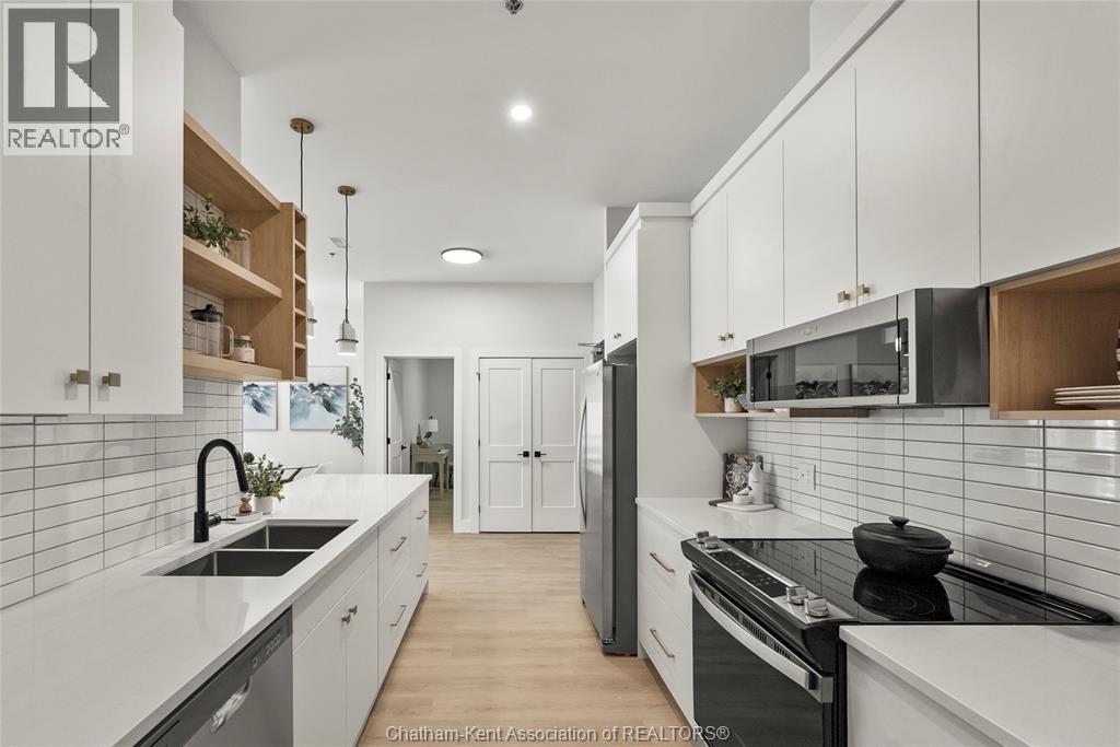 A modern kitchen with white cabinets and a wooden floor.