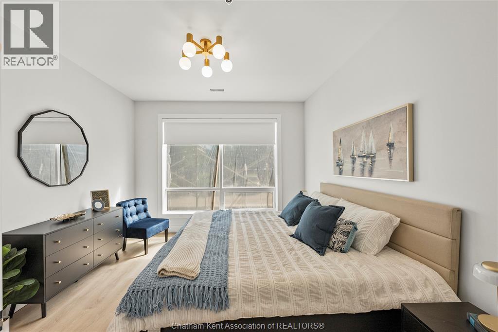 A bedroom with a large bed, a blue chair, and a mirror on the wall.