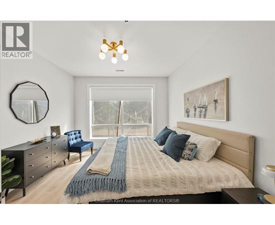 A bedroom with a large bed, a blue chair, and a mirror on the wall.