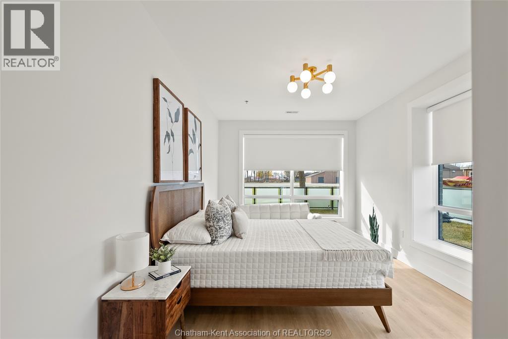A bedroom with a bed, nightstand, and a window overlooking a balcony.