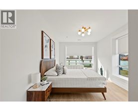 A bedroom with a bed, nightstand, and a window overlooking a balcony.