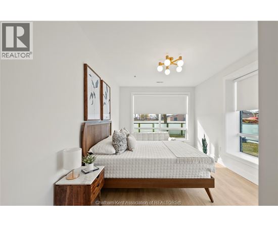 A bedroom with a bed, nightstand, and a window overlooking a balcony.