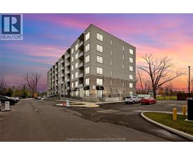 A large apartment building with a parking lot in front of it.
