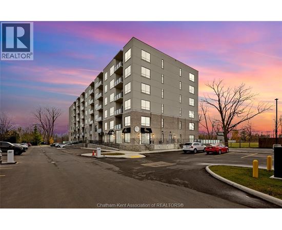 A large apartment building with a parking lot in front of it.