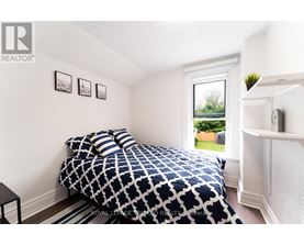A bedroom with a patterned bedspread and a window showing a green outdoor area.
