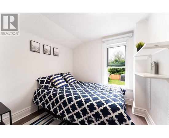 A bedroom with a patterned bedspread and a window showing a green outdoor area.