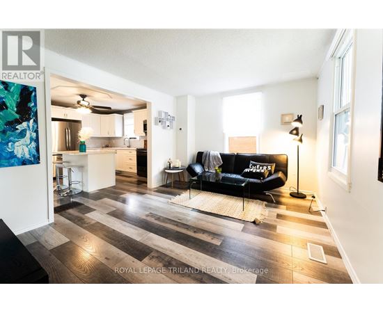 A living room with a black couch and a wooden floor.