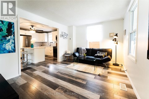 A living room with a black couch and a wooden floor.