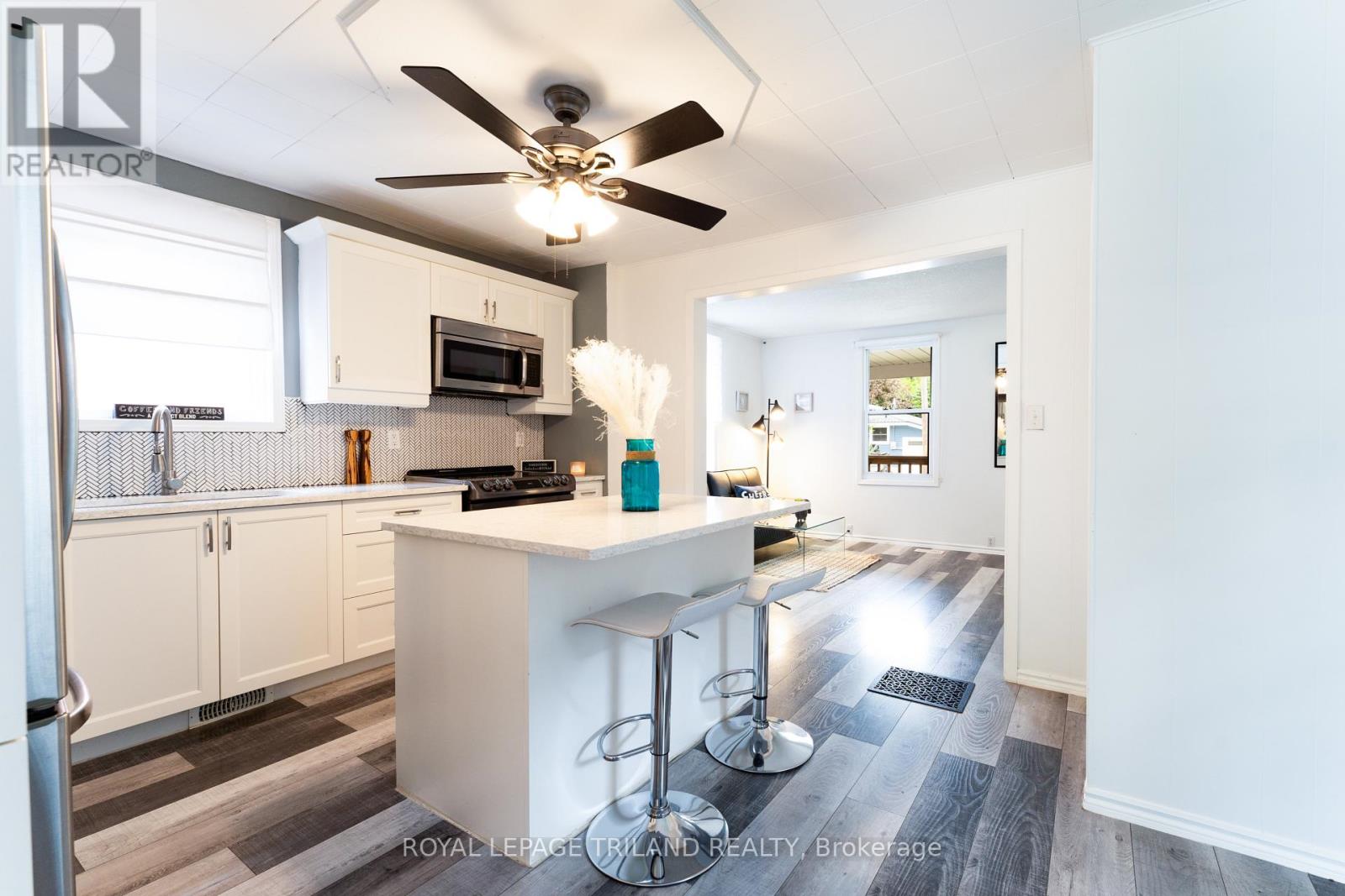 A kitchen with white cabinets and a white island with bar stools.